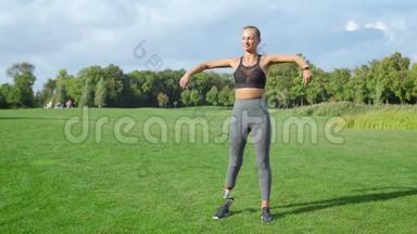 女运动员在公园锻炼前热身。 女人在绿色地区温暖手臂